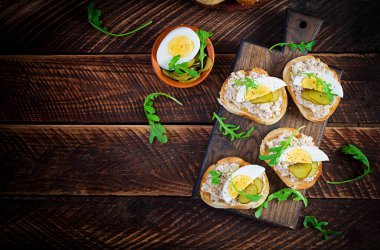 Ahşap kesme tahtasının üzerinde tuzlanmış morina balığı kremalı tost ekmeği. Kızarmış ekmeğin üzerine uskumru ezmesi. İskandinav mutfağı. Üst görünüm, genel görünüm