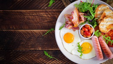 İngiliz kahvaltısı - kızarmış yumurta, fasulye, domates, sosis, pastırma ve tost. Üst görünüm, düz görünüm, genel görünüm