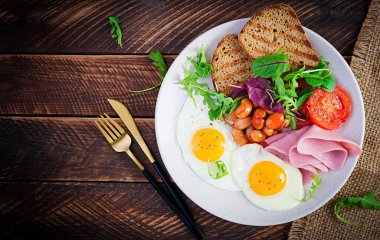 İngiliz kahvaltısı - kızarmış yumurta, fasulye, domates, sosis, jambon ve tost. Üst görünüm, düz görünüm, genel görünüm