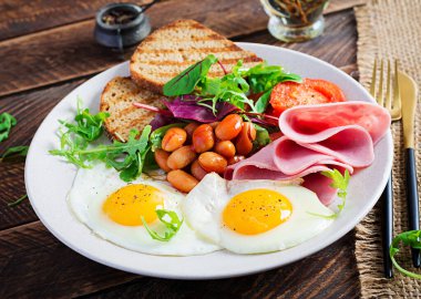 İngiliz kahvaltısı - kızarmış yumurta, fasulye, domates, sosis, jambon ve tost.