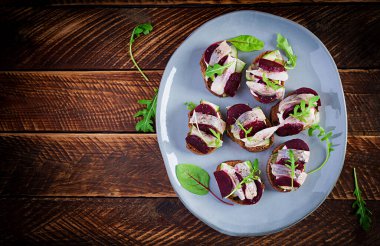 Ringa filetosu. Tuzlu ringa balıklı sandviç ve ahşap masadaki tostların üzerinde pancar kökü. İskandinav mutfağı. Üst görünüm, genel görünüm