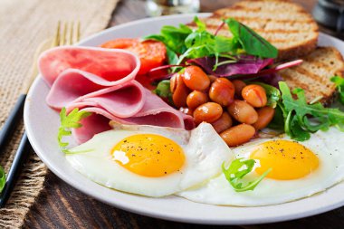İngiliz kahvaltısı - kızarmış yumurta, fasulye, domates, sosis, jambon ve tost.
