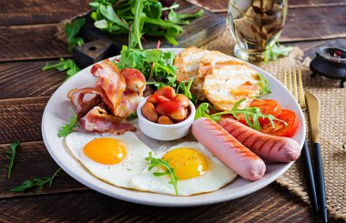 İngiliz kahvaltısı - kızarmış yumurta, fasulye, domates, sosis, pastırma ve tost.