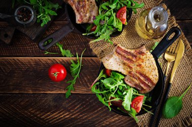 Tahta arka planda kemiğe otlar sürülmüş sulu ızgara domuz bifteği. Üst görünüm, genel görünüm, düz görünüm