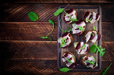 Ringa filetosu. Tuzlu ringa balıklı sandviç ve tahta kesme tahtasının üstünde pancar kökü. İskandinav mutfağı. Üst görünüm, genel görünüm