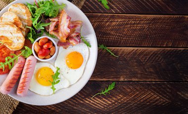 İngiliz kahvaltısı - kızarmış yumurta, fasulye, domates, sosis, pastırma ve tost. Üst görünüm, düz görünüm, genel görünüm