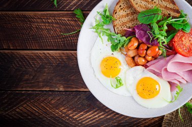 İngiliz kahvaltısı - kızarmış yumurta, fasulye, domates, sosis, jambon ve tost. Üst görünüm, düz görünüm, genel görünüm