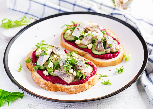 鲱鱼片 夹杂着咸鱼和甜菜的三明治放在白盘上的烤面包上 斯堪的纳维亚料理 — 图库照片