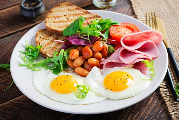 İngiliz kahvaltısı - kızarmış yumurta, fasulye, domates, sosis, jambon ve tost.