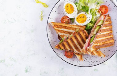 Jambon, domates, peynir, avokado ve bir fincan kahveyle ızgara sandviç sandviçi. Lezzetli kahvaltı ya da atıştırmalık. Üst manzara, düz uzanma