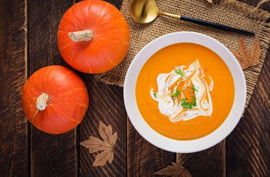 Kırsal ahşap masada balkabağı çorbası. Mevsimlik sonbahar yemekleri, baharatlı balkabağı ve havuç çorbası. Üst görünüm, düz görünüm, kopyalama alanı