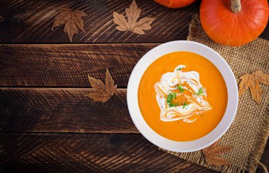 Kırsal ahşap masada balkabağı çorbası. Mevsimlik sonbahar yemekleri, baharatlı balkabağı ve havuç çorbası. Üst görünüm, düz görünüm, kopyalama alanı