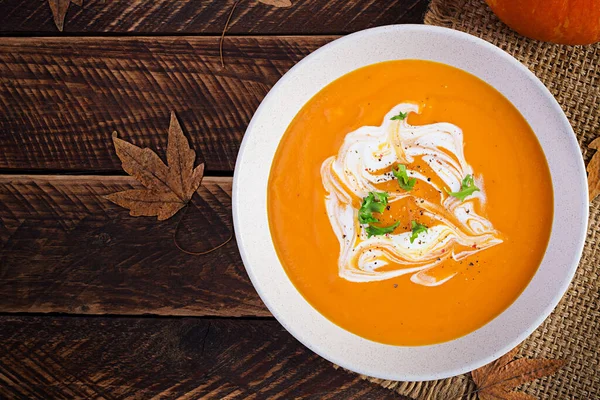 Kırsal ahşap masada balkabağı çorbası. Mevsimlik sonbahar yemekleri, baharatlı balkabağı ve havuç çorbası. Üst görünüm, düz görünüm, kopyalama alanı