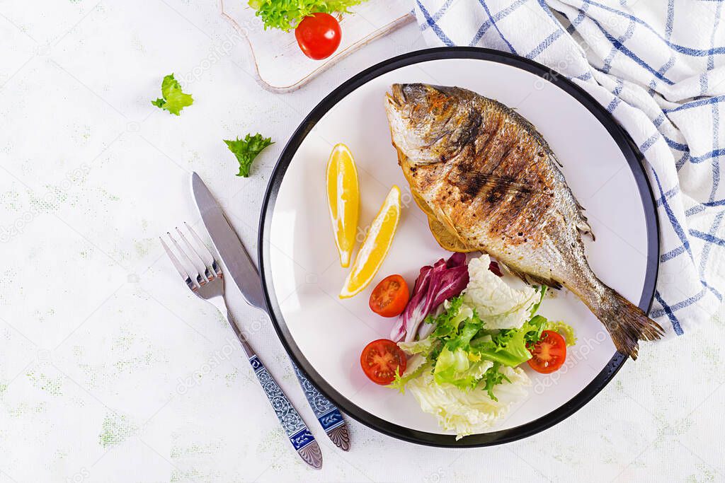 Delicious grilled dorado or sea bream fish with salad, spices, grilled dorada on a plate. Top view, overhead, copy space