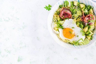 Ketogenik, paleo diyeti. Yağda yumurta, jambon, avokado ve taze salata. Keto kahvaltısı. Brunch olsun. Üst görünüm, genel görünüm, düz görünüm