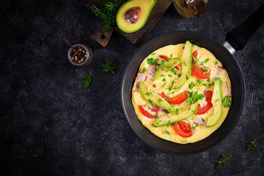 Keto kahvaltısı. Jambonlu omlet, domates ve gri masada avokado. İtalyan omleti. Keto, ketojenik öğle yemeği. Üst görünüm, genel görünüm, kopyalama alanı