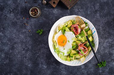 Ketogenik, paleo diyeti. Yağda yumurta, jambon, avokado ve taze salata. Keto kahvaltısı. Brunch olsun. Üst görünüm, genel görünüm, düz görünüm