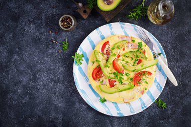 Keto kahvaltısı. Jambonlu omlet, domates ve gri masada avokado. İtalyan omleti. Keto, ketojenik öğle yemeği. Üst görünüm, genel görünüm, kopyalama alanı