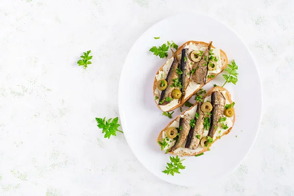 Sandwich - smorrebrod with sprats, green olives and butter on light table. Danish cuisine. Top view, overhead, flat lay — Stock Image Sandwich Smorrebrod Sprats Green Olives Butter Light Table Danish Cuisine Royalty Free Stock Photos