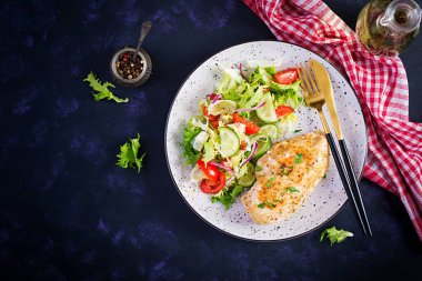 Ketogenik, keto yemeği. Kızarmış tavuk fileto ve taze sebze salatası, salatalık ve marul. Salatalı tavuk eti. Sağlıklı yiyecekler. Üst görünüm, düz görünüm, kopyalama alanı