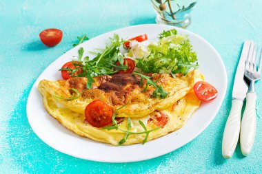 Kahvaltıda. Beyaz tabakta domatesli omlet, peynir ve roka. Frittata - İtalyan omleti. Ketogenik, keto yemeği..