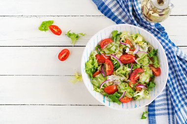 Salatalıklı taze domates, marul, kırmızı soğan ve beyaz kasede baharat. Sağlıklı bir aperatif. Beyaz ahşap arka plan. Üst görünüm, genel görünüm, kopyalama alanı