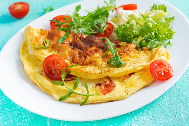 Kahvaltıda. Beyaz tabakta domatesli omlet, peynir ve roka. Frittata - İtalyan omleti. Ketogenik, keto yemeği..