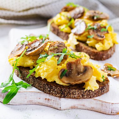 Çırpılmış yumurta ve kızarmış mantar. Ev yapımı kahvaltı ya da brunch yemeği - çırpılmış yumurta ve mantarlı sandviç..