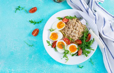 Kahvaltı yulaf lapası haşlanmış yumurta, vişneli domates ve roka. Sağlıklı dengeli yiyecekler. Üst görünüm, yukarıda, boşluğu kopyala