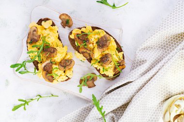 Çırpılmış yumurta ve kızarmış mantar. Ev yapımı kahvaltı ya da brunch yemeği, çırpılmış yumurta ve mantarlı sandviç. Üst görünüm, genel görünüm, kopyalama alanı