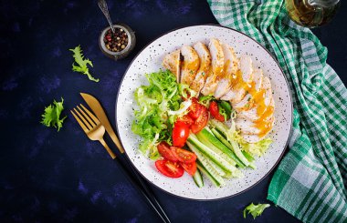 Ketogenik, keto yemeği. Kızarmış tavuk fileto ve taze sebze salatası, salatalık ve marul. Salatalı tavuk eti. Sağlıklı yiyecekler. Üst görünüm, düz görünüm, kopyalama alanı