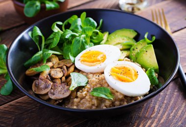 Kahvaltı yulaf lapası haşlanmış yumurta, avokado ve kızarmış mantar. Sağlıklı dengeli yiyecekler.