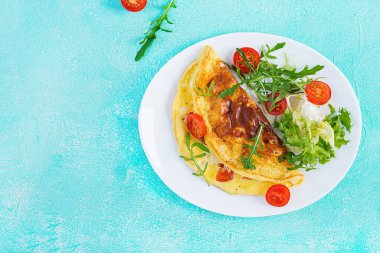 Kahvaltıda. Beyaz tabakta domatesli omlet, peynir ve roka. Frittata - İtalyan omleti. Ketogenik, keto yemeği. Üst manzara, düz uzanma