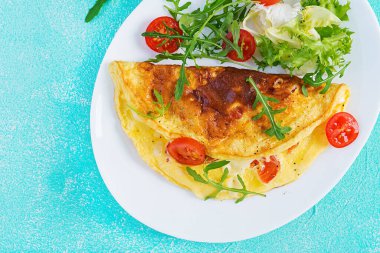 Kahvaltıda. Beyaz tabakta domatesli omlet, peynir ve roka. Frittata - İtalyan omleti. Ketogenik, keto yemeği. Üst manzara, düz uzanma