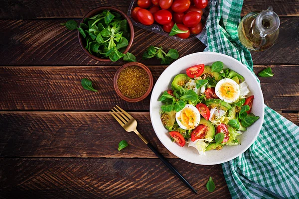 Fresh avocado salad with tomato, avocado, boiled eggs and fresh lettuce. Ketogenic diet breakfast.  Keto, paleo salad. Top view, overhead, above