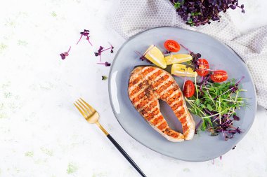 Somon balığı. Somon balığı bifteği ızgara ve mikroyeşillikli domates salatası. Sağlıklı yiyecekler. Üst görünüm, genel görünüm, kopyalama alanı.