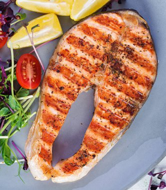 Somon balığı. Somon balığı bifteği ızgara ve mikroyeşillikli domates salatası. Sağlıklı yiyecekler. Üst görünüm, genel görünüm, kopyalama alanı.