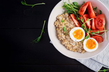 Kahvaltı yulaf lapası haşlanmış yumurta, kiraz domatesleri ve mikroyeşillikler. Sağlıklı dengeli yiyecekler. Üst görünüm, yukarıda, boşluğu kopyala