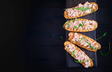 Fırında somon balığıyla Tapas. Somon soslu sandviç, peynir, avokado, domates ve kırmızı soğan. Riyet somonlu tost. Üst görünüm, genel görünüm, kopyalama alanı