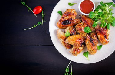 Izgara tavuk kanadı. Ahşap masada fırında tavuk kanadı. Masa ayarı. Üst görünüm, düz görünüm, genel görünüm