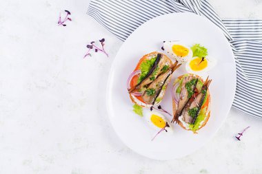 Sandviç, sprat, avokado, domates, yumurta ve krem peynirli beyaz tabak. Danimarka mutfağı. Üst manzara, genel giderler. Çevre dostu kavram.