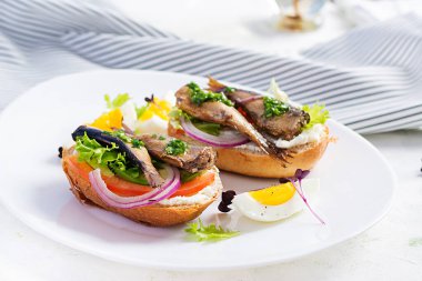 Sandviç, sprat, avokado, domates, yumurta ve krem peynirli beyaz tabak. Danimarka mutfağı. Çevre dostu kavram.