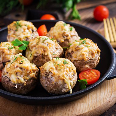 Tavukla doldurulmuş fırında mantar kıyma, peynir ve otlar ahşap bir arka planda.