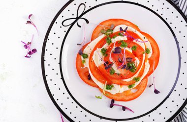 Caprese salatası. Mozzarella peyniri, domates ve tabakta fesleğen pesto. Üst manzara, genel giderler. Çevre dostu kavram.