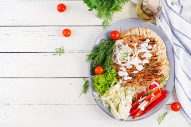 Pide ile ızgara tavuk kebabı, beyaz bir masada taze sebzeler. Izgara et şiş, beyaz arka planda şiş kebap. Üstten, üstten, düz.