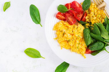 Kahvaltıda. Çilekli yumurta, domates, ıspanak ve mısır. Üstten, düz, üstten