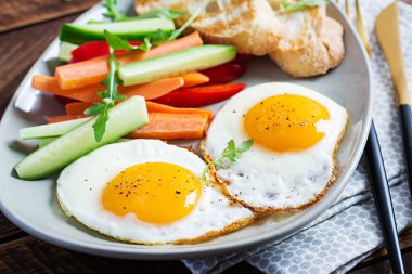 Kahvaltıda. Taze havuçlu yumurta, salatalık, kırmızı biber ve ahşap zemin üzerinde kızarmış ekmek. Vejetaryen yemeği.