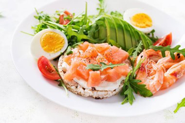 Ketogenik diyet kahvaltısı. Haşlanmış karides, karides, domates, roka, yumurta ve avokado ile tuzlu somon salatası. Keto, öğle yemeği..