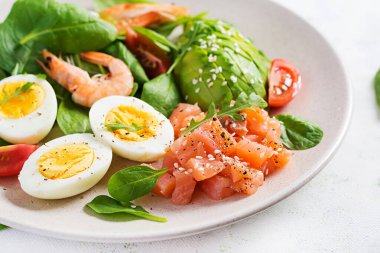 Ketogenik diyet kahvaltısı. Haşlanmış karides, karides, domates, ıspanak, yumurta ve avokado ile tuzlu somon salatası. Keto, öğle yemeği..