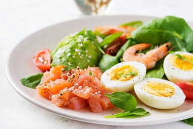 Ketogenik diyet kahvaltısı. Haşlanmış karides, karides, domates, ıspanak, yumurta ve avokado ile tuzlu somon salatası. Keto, öğle yemeği..